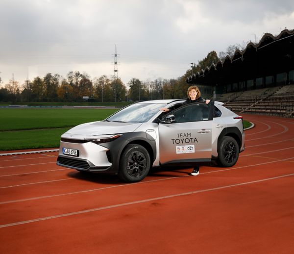 Ulrike Nasse-Meyfarth steig in einen silbernen Toyota bZ4X, der auf einer Tartanbahn in einem Stadion steht