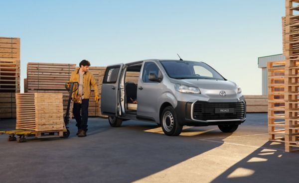 Person entlädt Holzpaletten mit einem Hubwagen aus einem silbernen Toyota Proace