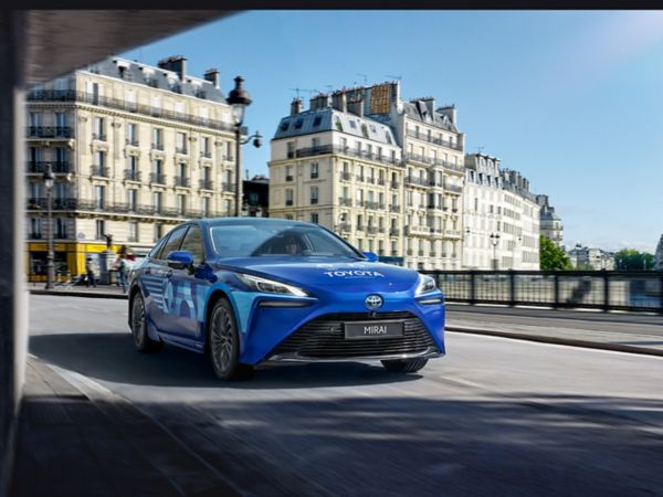 Şehirde ilerleyen mavi Toyota Mirai