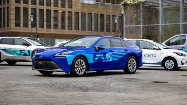 kadrajda Mavi Toyota Mirai ve bir dizi Toyota model araçların görüntüsü