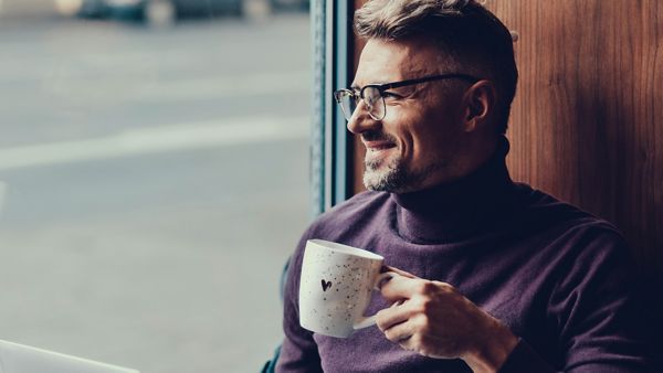 Man looking out the window while holding cup