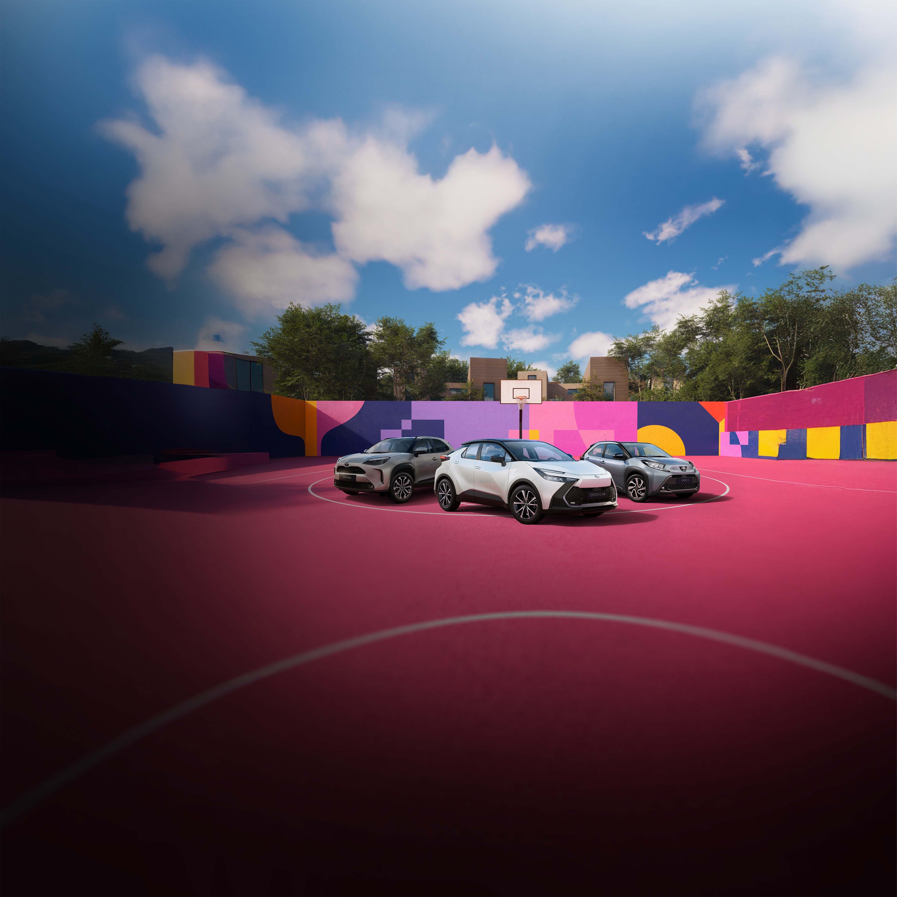 Vier Toyotas stehen auf einem pinken Basketballplatz, der von einer bunt bemalten Wand umgeben ist.