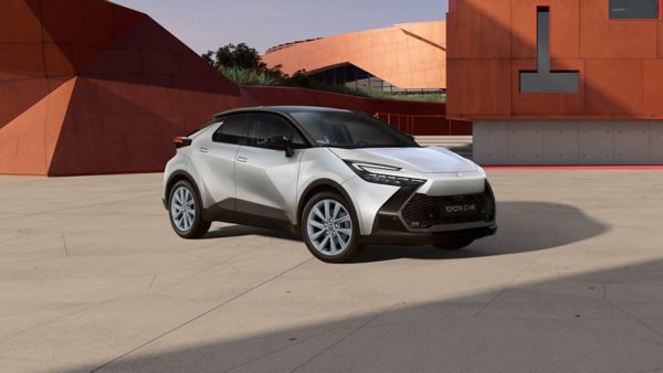 Weißer Toyota C-HR steht vor einem bronzenem Gebäude