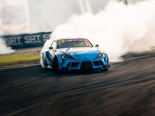 Blauer Sportwagen von Toyota driftet auf einer Rennstrecke um eine Kurve. Durch den Reifenabrieb entsteht weißer Qualm hinter dem Fahrzeug.