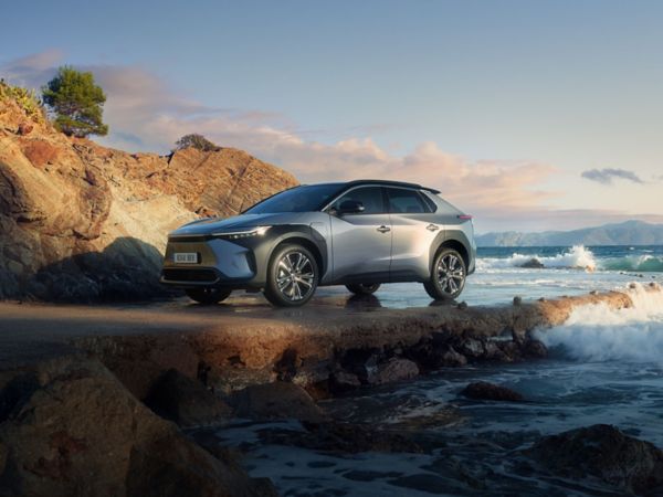 Toyota SUV steht geparkt an einem felsigen Strand, auf dem sich die Wellen brechen.