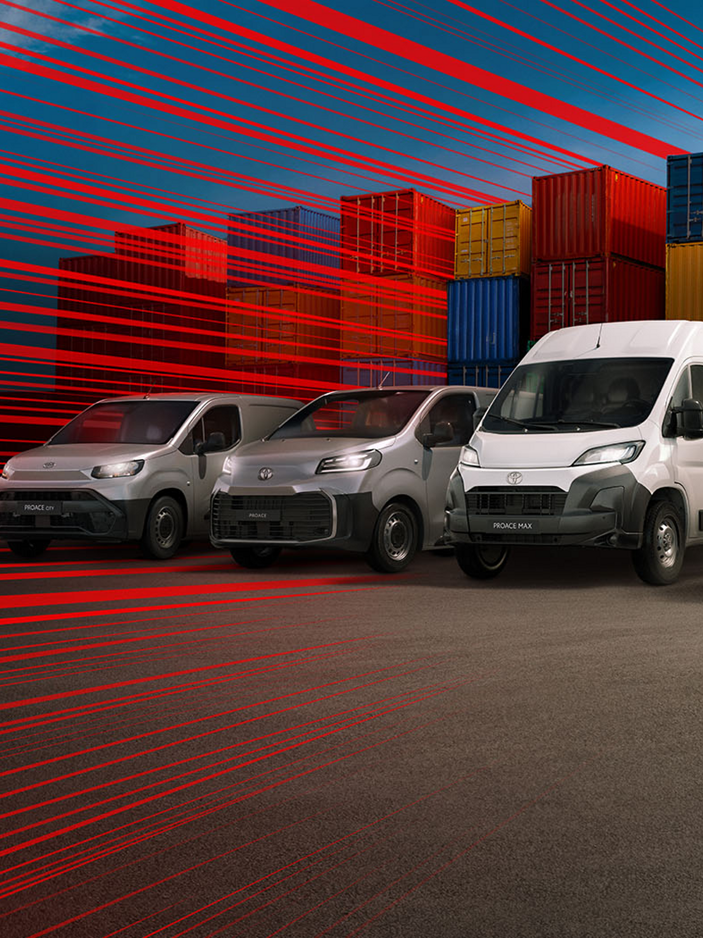 Hilux, Proace Max, Proace und ein Proace City schräg von vorn auf einem Parkplatz, umgeben von Stapeln aus Europaletten, daneben Ladesäulen