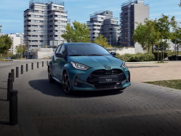 Ein grüner Toyota fährt auf einer Straße in der Stadt, im Hintergrund sind Hochhäuser und Bäume zu sehen