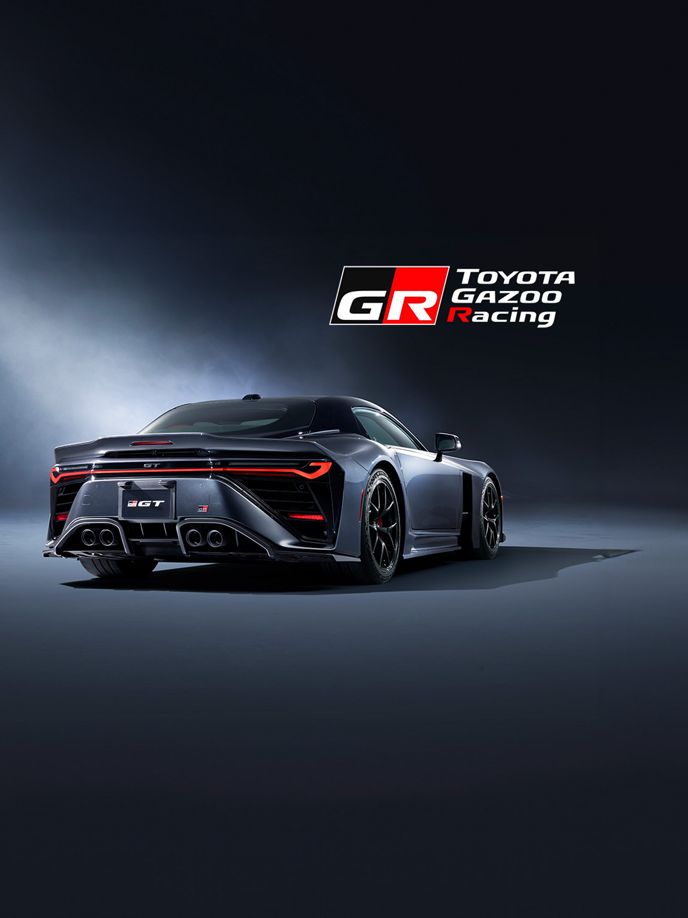 Das Heck des neuen GR GT mit markanten, roten Bremslichtern, vier Auspuffrohren und Belüftungsschlitzen unterstreicht die Sportlichkeit des Autos. Im oberen rechten Bildrand steht das rote Logo von Toyota Gazoo Racing.