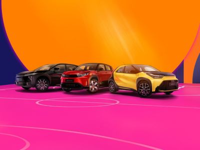 Drei Fahrzeuge von Toyota stehen auf einem pinken Basketballfeld. Die Wände sind in bunten Formen dekoriert.