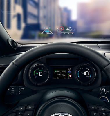 Nahaufnahme eines Lenkrads und Armaturenbrettanzeige mit einem Head-up-Display, welches an der Windschutzscheibe angezeigt wird.
