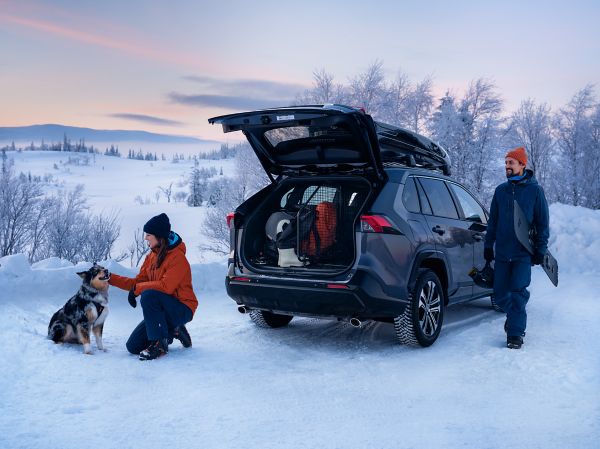 SUV-Auto mit geöffneter Heckklappe und Winterausrüstung in verschneiter Landschaft.