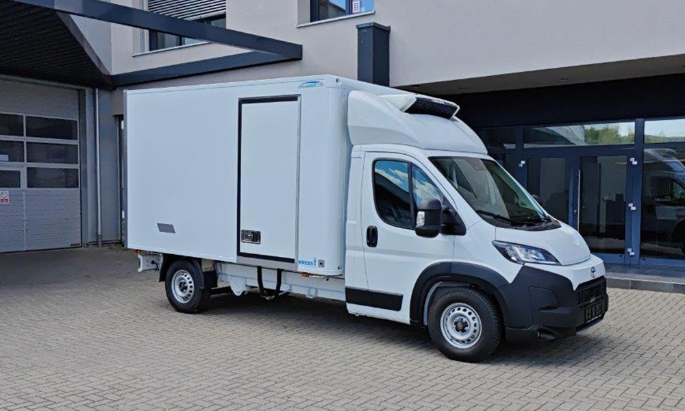 Weißer Toyota Transporter vor einem Werkstattgebäude.