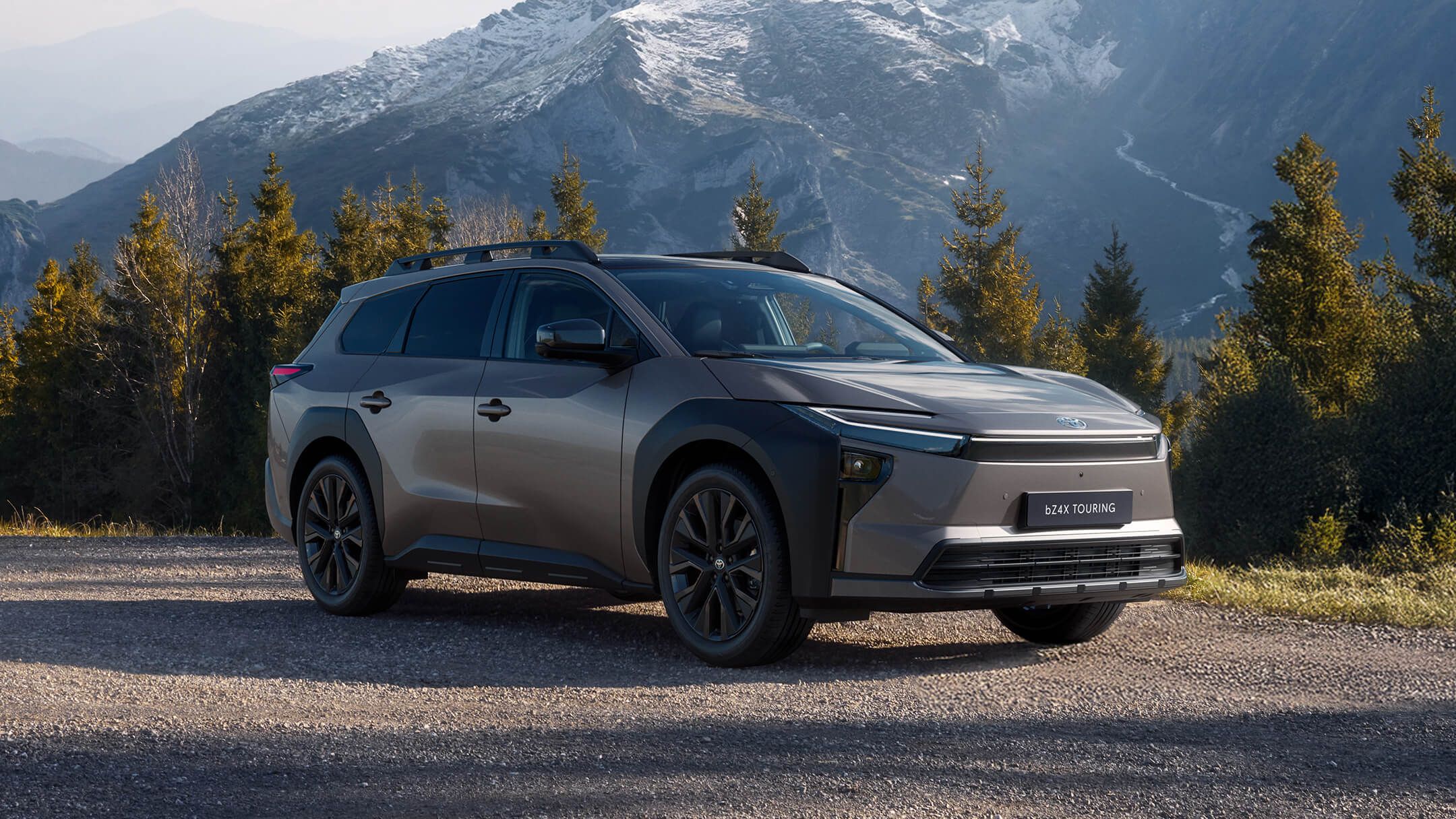 Silberner Elektro-SUV steht auf einem Parkplatz an einer Ladesäule. Im Hintergrund ist ein begrüntes Büro-Gebäude zu sehen.