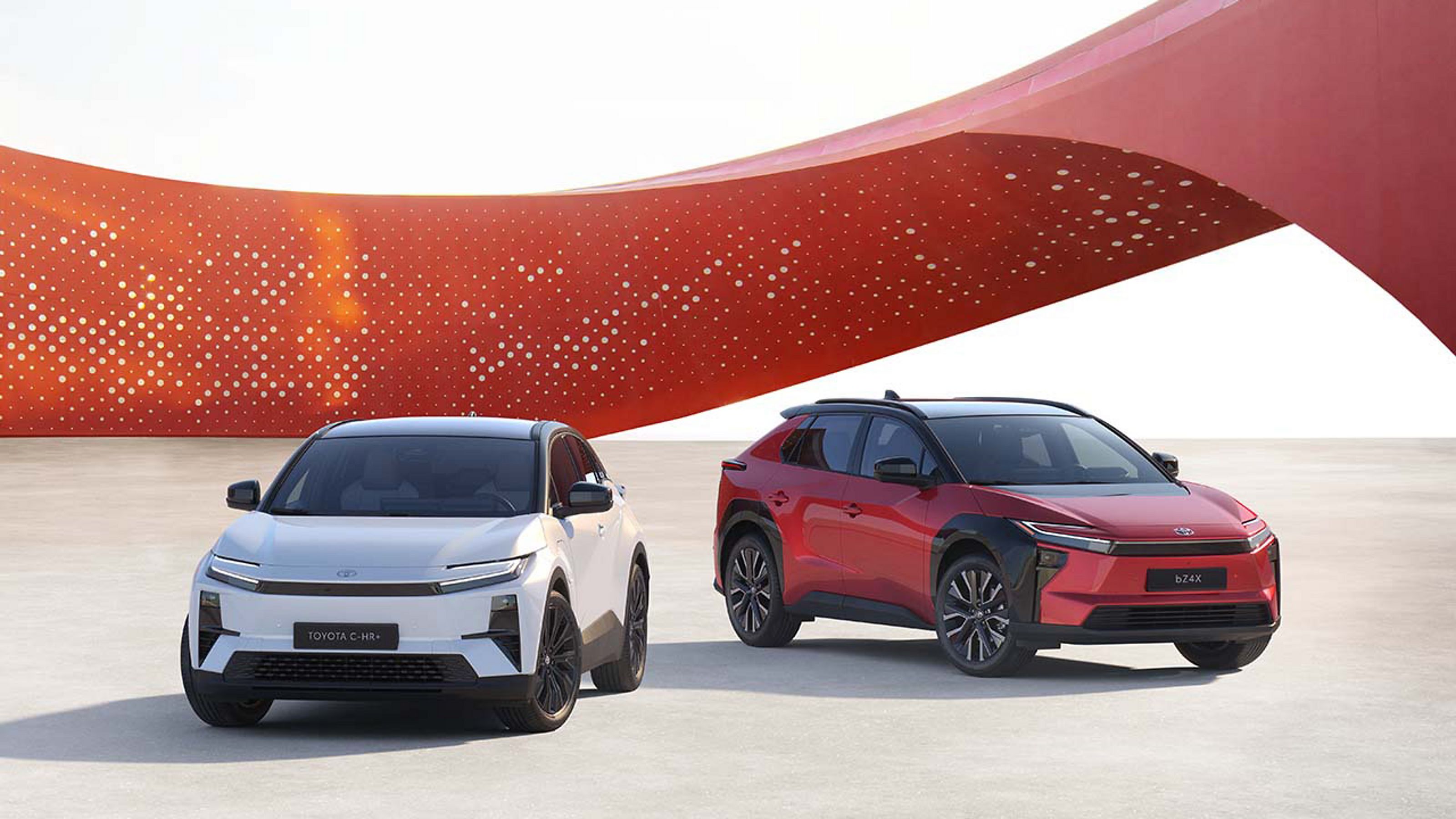 Toyota C-HR+ und Toyota bZ4X vor modernem roten Hintergrund.