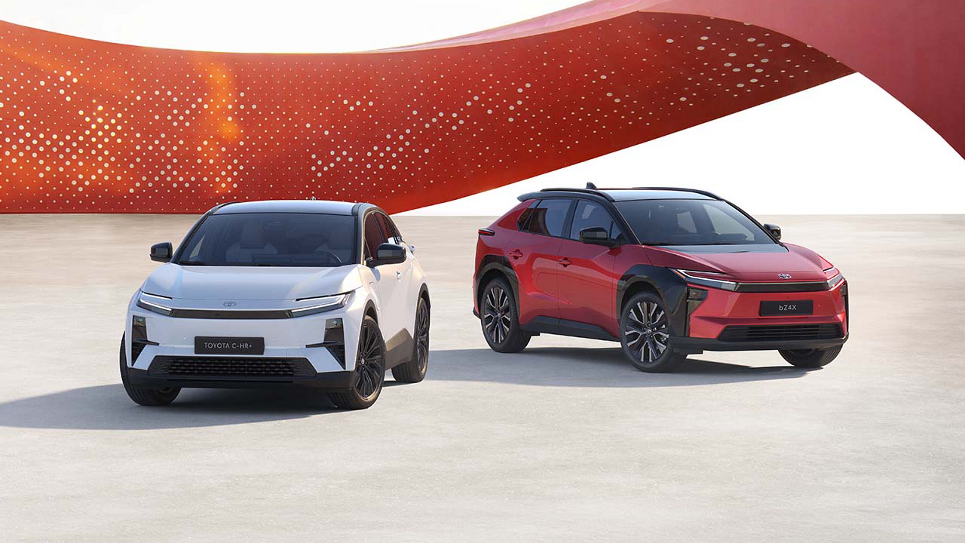 Toyota C-HR+ und Toyota bZ4X vor modernem roten Hintergrund.
