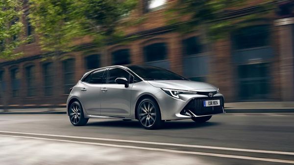 Toyota Kompaktwagen fährt durch eine mit Bäumen gesäumte Straße