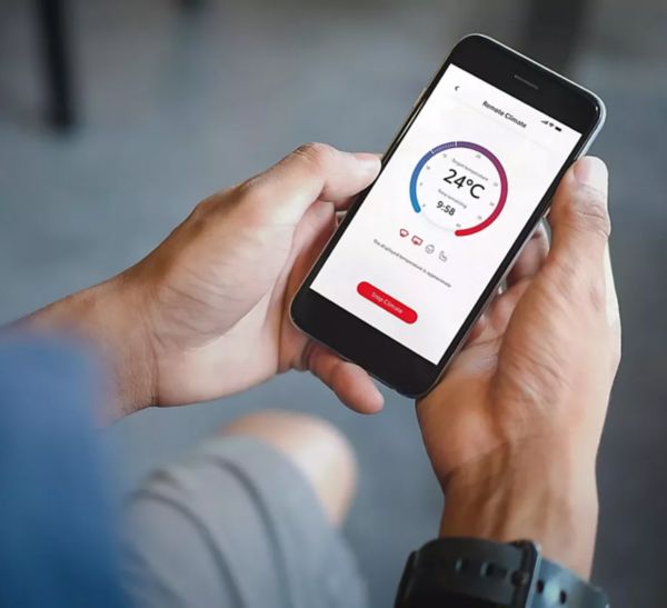 Smartphone in der Hand einer Person, darauf eine App zum Bedienen der Klimatisierung zu sehen