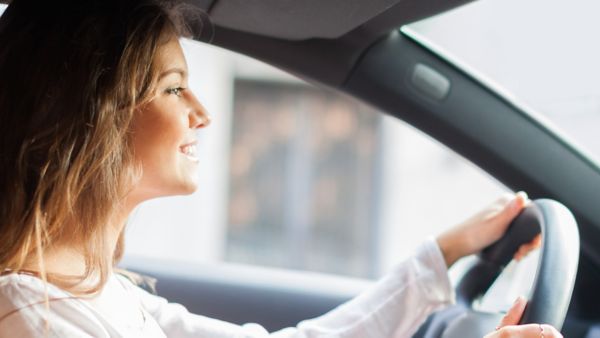 Seitliche Perspektive auf eine Person am Steuer eines Fahrzeugs, die lächelt