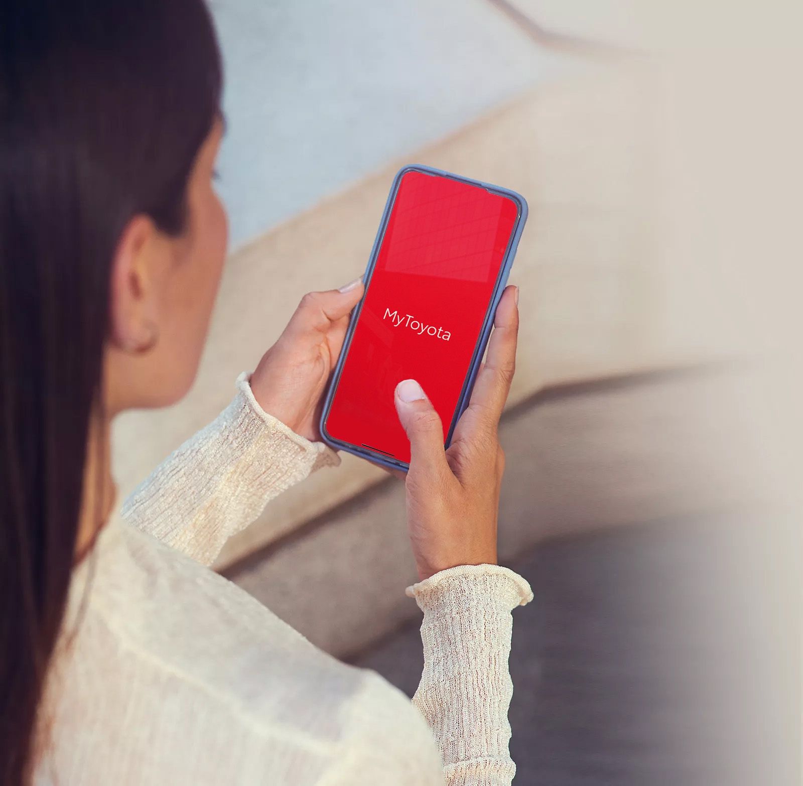 Blick von erhöhter Position über die Schulter einer jungen Frau, die auf Ihrem Smartphone eine App geöffnet hat