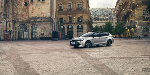 Silberner Toyota Corolla Touring Sports steht diagonal zur Kamera auf einem gepflasterten Platz
