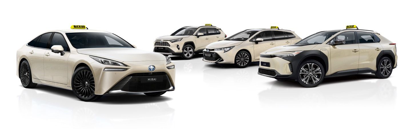 Eine Reihe von vier beigefarbenen Toyota-Taxis, darunter der Toyota Mirai und weitere Hybridmodelle vor einem weißen Hintergrund.
