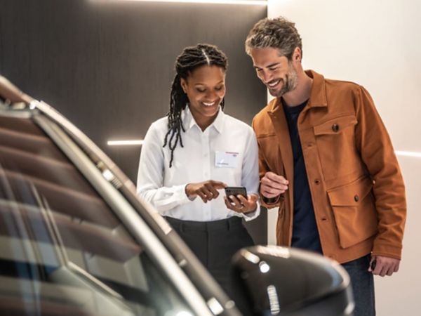 Verkäuferin berät einen Kunden in einem Autohaus