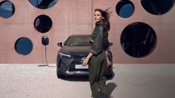 Eine Person steht neben einem geparkten Lexus UX , der gerade aufgeladen wird