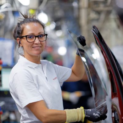 une femme travaillant à l'usine tmmf qui tient une vitre de voiture