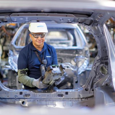 un homme travaillant sur un chassis de toyota à l'usine tmmf