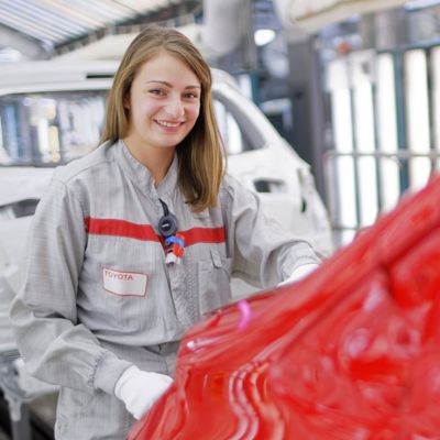 une femme souriante travaillant sur une toyota à l'usine tmmf