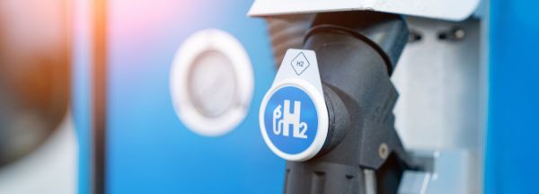 Eine Zapfpistole für Wasserstoffautos an einer blauen H₂-Tankstation verdeutlicht die Nutzung alternativer Antriebstechnologien.