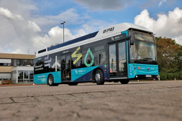 Hauptsächlich blauer Linienbus mit diversen Aufdrucken von schräg vorn aus der Froschperspektive auf einer Asphaltfläche fotografiert