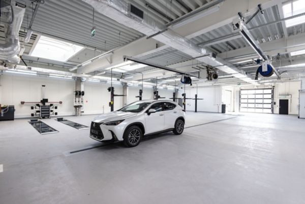 A Lexus mechanic walking past a parked Lexus RZ with a case in hand