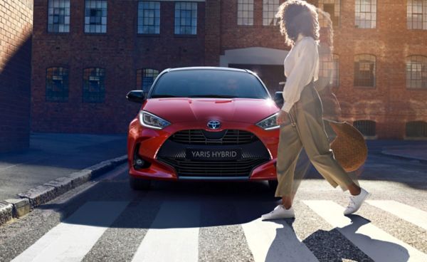 a person walking past a Toyota Yaris on a zebra crossing