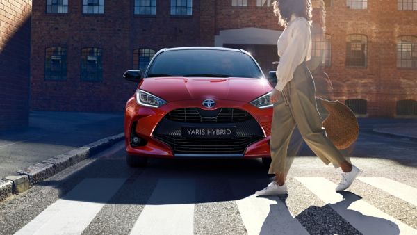 Toyota yaris hybrid with a woman walking past