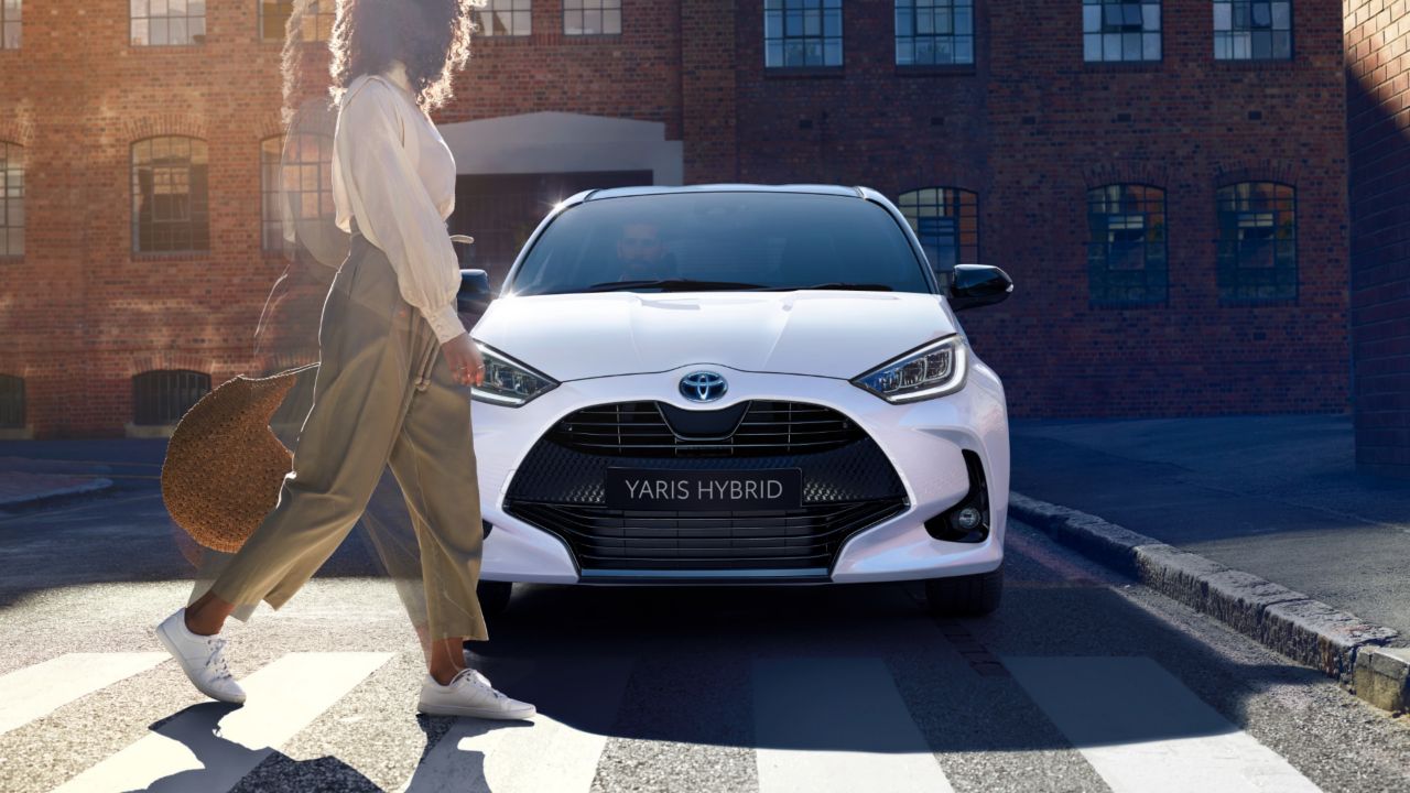 Woman walking past a Toyota Yaris Hybrid