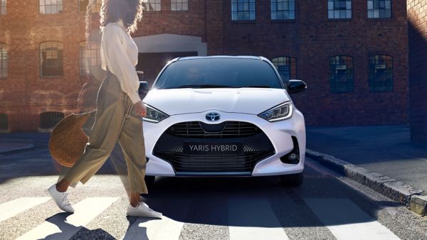 Woman walking past a Toyota Yaris Hybrid